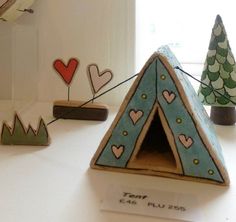 a close up of a cake shaped like a tent with trees and hearts on it