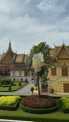 a large building with many plants in front of it and a palm tree on the other side