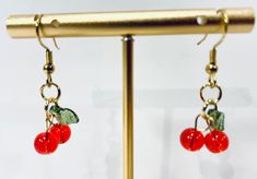 Red Cherry Earrings ! Great find and affordable for a special gift or to treat yourself . Earrings length is a little over 1.5 inches . Cherries are too cute ! Appropriate for any age . Small red cherries 6mm with green leaf hanging from goldtone fish hook ear wires .  Thanks for stopping by . Please come again for holiday shopping, desks and free shipping over $35 order  . New listings coming at all times ! Cherry Earrings, Red Cherry, Holiday Shopping, Green Leaf, Fish Hook, Lake City, Ear Wires, Special Gift, Green Leaves