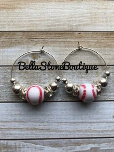 two hoop earrings with red and white balls on them, hanging from a wooden background