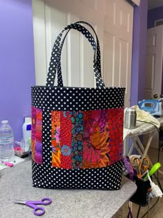 a black and white polka dot bag sitting on top of a counter next to scissors