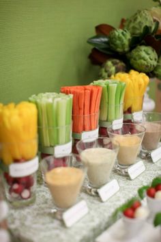 a table topped with lots of different types of food and drink cups filled with vegetables