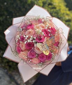 a person holding a bouquet of flowers with a butterfly on the top of it in their hand