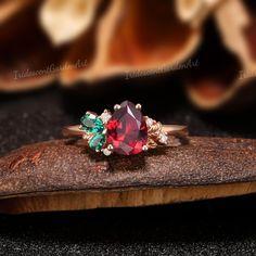 a red and green ring sitting on top of a piece of wood next to flowers