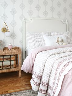 a bedroom with a bed, nightstand and wallpaper in white and pink color scheme