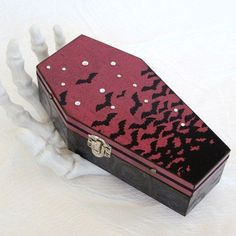 a decorative box with black and red designs on it's lid sitting on a white surface