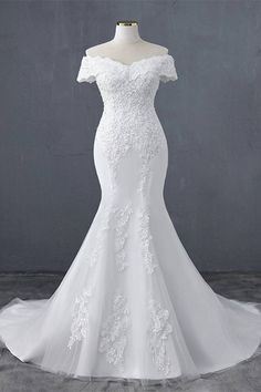 a white wedding dress on a mannequin with an off the shoulder neckline