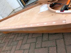 a wooden boat sitting on top of a brick floor next to a building with tools in it