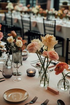 the table is set with flowers in vases and place settings for two people to sit at