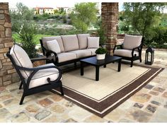 an outdoor patio furniture set with beige cushions and black frame, sitting on a stone patio