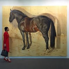 a woman walking past a painting of a horse