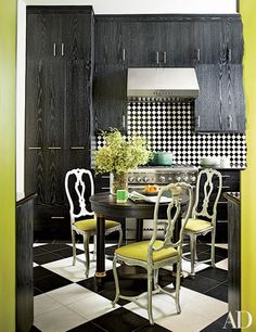 a kitchen with black and white checkered flooring, yellow chairs and an oven