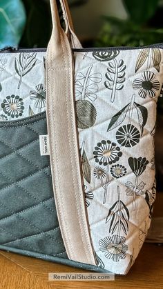 a close up of a purse on a table with a plant in the back ground