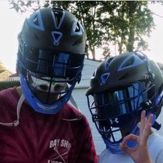 two young boys wearing helmets and making the peace sign with their hands while standing next to each other