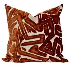 a brown and white pillow with an abstract design on the front, sitting on a white background