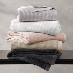 folded towels stacked on top of each other in front of a gray and white wall