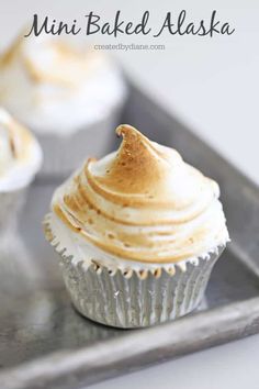 two cupcakes with white frosting on a metal tray