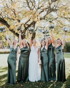 a group of women standing next to each other in front of a tree