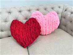 two knitted hearts sitting on top of a couch