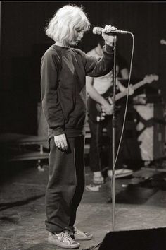 an old black and white photo of a person on stage with a microphone in front of him