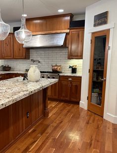 a kitchen with wooden cabinets and marble counter tops, along with wood flooring that matches the hardwood floors