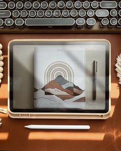 a desk with a keyboard, pen and paper on it