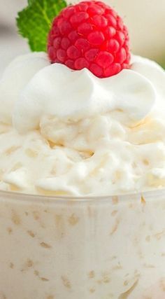 a close up of a bowl of food with whipped cream and a raspberry on top