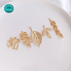 three gold leaf charms sitting on top of a white plate