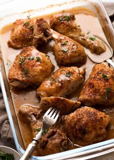 a pan filled with chicken legs covered in gravy and garnished with parsley