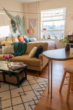 a living room filled with furniture next to a wooden table and two stools on top of a hard wood floor