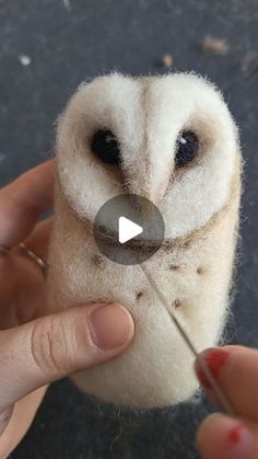 someone is holding an owl toy with a needle in it's mouth and pointing at the button