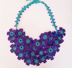 This floral statement necklace is a purple necklace for women and girls. It is crocheted with organic cotton thread. This flower bib necklace is crocheted with love. It is completely our own design. This oya jewelry is made of cotton thread, beads and crochets. It has 4 strands decorated with purple beads. The purple flowers in the necklace are very dense and it makes this beaded crochet necklace dainty. The measures of floral bib necklace are; length 65 cm, height 25 cm and width 16 cm. All connections parts are made of cotton thread. Metal is not used in this purple floral bib necklace. It can be customized in different colors or lengths. This beaded bib necklace is natty and elegant. With crochet oya necklace, you will not need to spend an effort to look sharp. It will look fashionable Purple Bohemian Crochet Jewelry, Handmade Purple Necklaces For Beach, Handmade Purple Beach Necklaces, Handmade Purple Bohemian Flower Necklace, Handmade Bohemian Purple Flower Necklace, Adjustable Purple Flower Necklace, Handmade Adjustable Purple Flower Necklace, Handmade Purple Flower Necklace For Gift, Bohemian Purple Flower Necklace