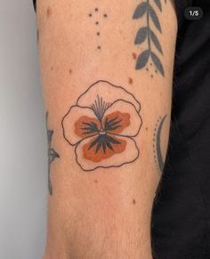 a close up of a person's arm with a flower tattoo on it