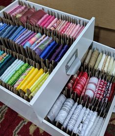 an open drawer with many different types of thread in it