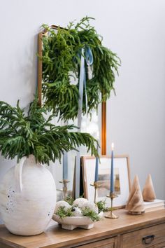 a white vase sitting on top of a wooden table next to a mirror and candles