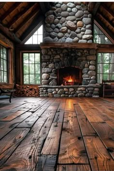 an empty room with wood floors and stone fireplace