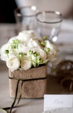 a bouquet of white flowers sitting on top of a table next to a place card holder