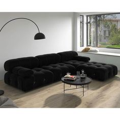 a living room filled with black furniture and a large window overlooking the street side area