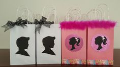 three paper bags decorated with silhouettes of people and pink feathers on top of a table