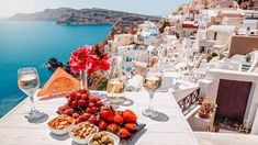 a table topped with fruit and wine next to the ocean