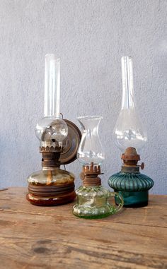 three glass vases sitting on top of a wooden table next to an old clock