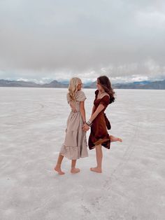 two women are walking in the desert holding hands