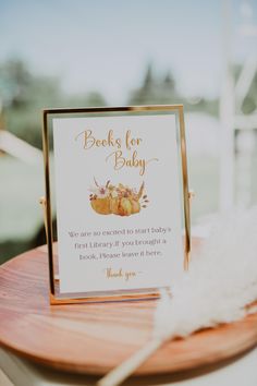 a book for baby sign sitting on top of a wooden table next to a white feather