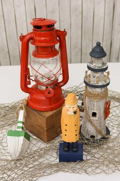 two small lighthouses are sitting on a table next to a red lantern and other items