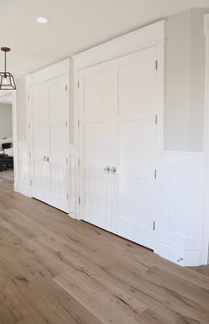 an empty room with white doors and hard wood flooring on the side of it