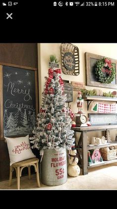 a decorated christmas tree in a bucket next to a chalkboard with merry christmas written on it