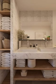 a bathroom with marble counter tops and shelves filled with white plates, napkins and baskets