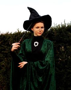 a woman dressed as a wizard holding an umbrella in her hand and wearing a green cloak