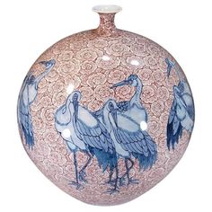 a blue and white vase with two birds on it's side, sitting in front of a white background