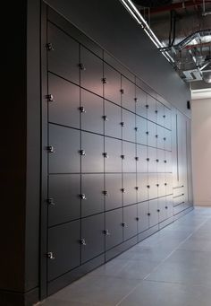 an empty room with many metal lockers on the wall and lights above each door